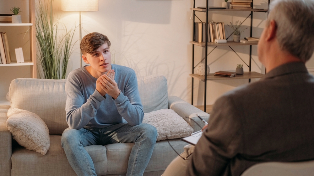 Mental Health Young man discussing mental health treatment with therapist.